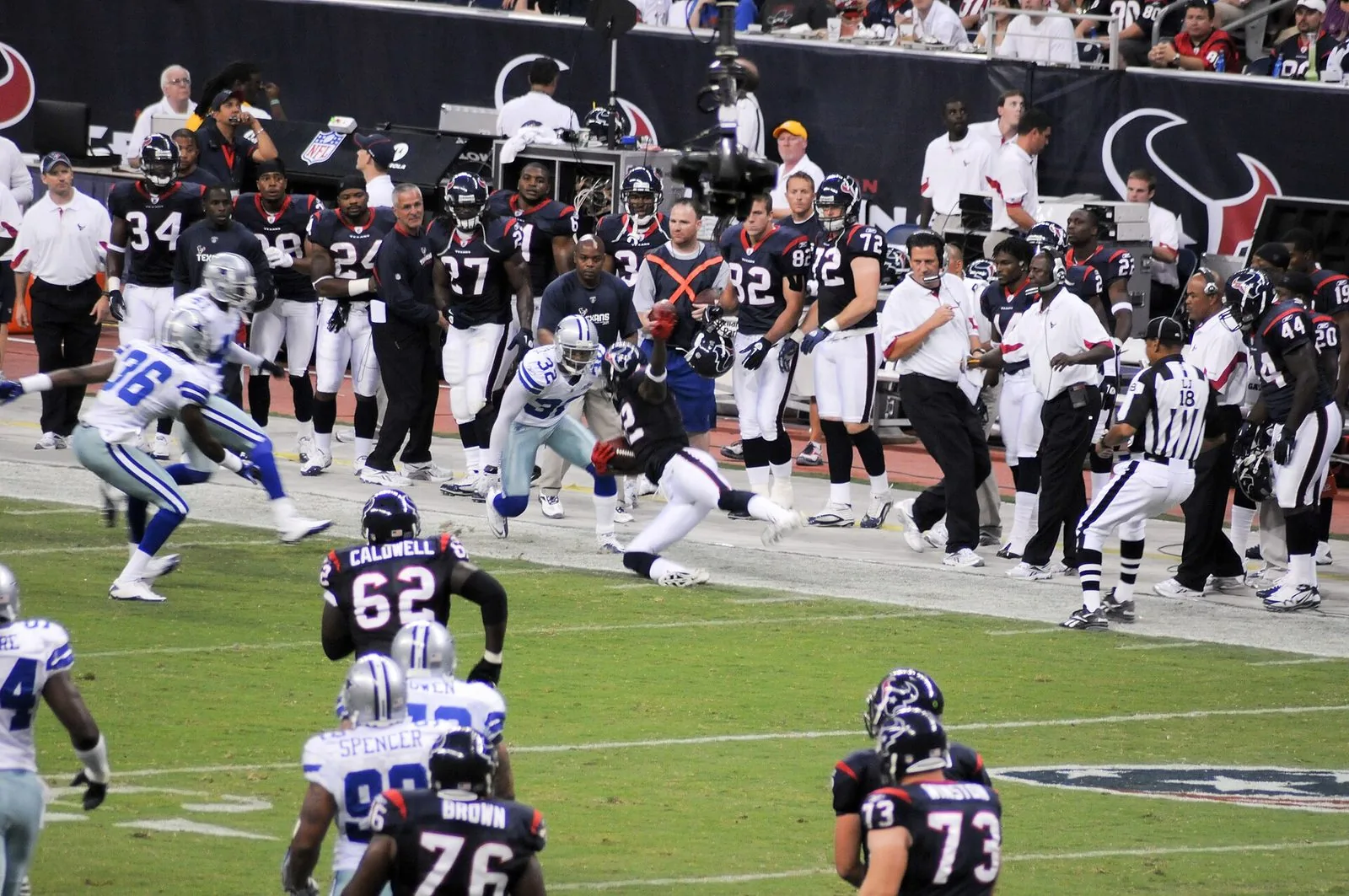 NFL players and staff on the sideline during a preseason game
